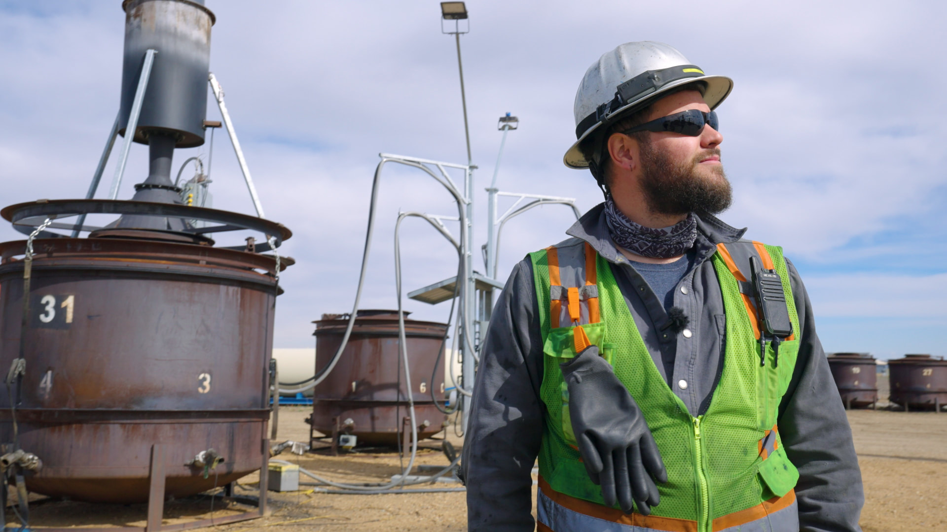 Biochar Now site worker in a hard hat and safety vest beside biochar production vessels
